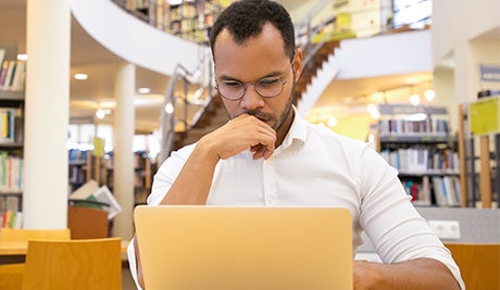novelist select promo slider male on laptop in library    